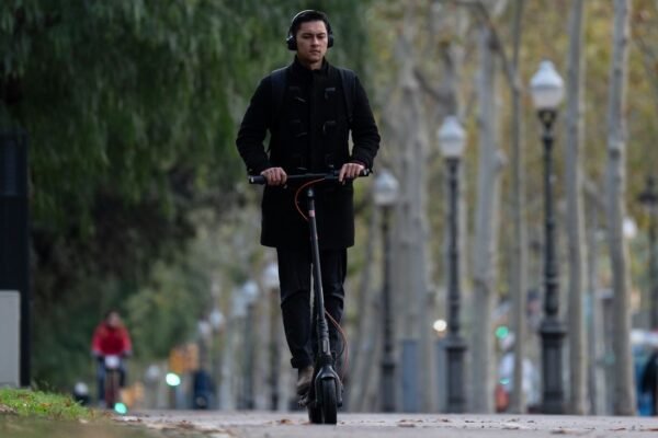 Una persona en patinete circulando con ariculares