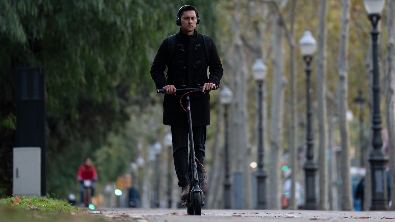 Una persona en patinete circulando con ariculares